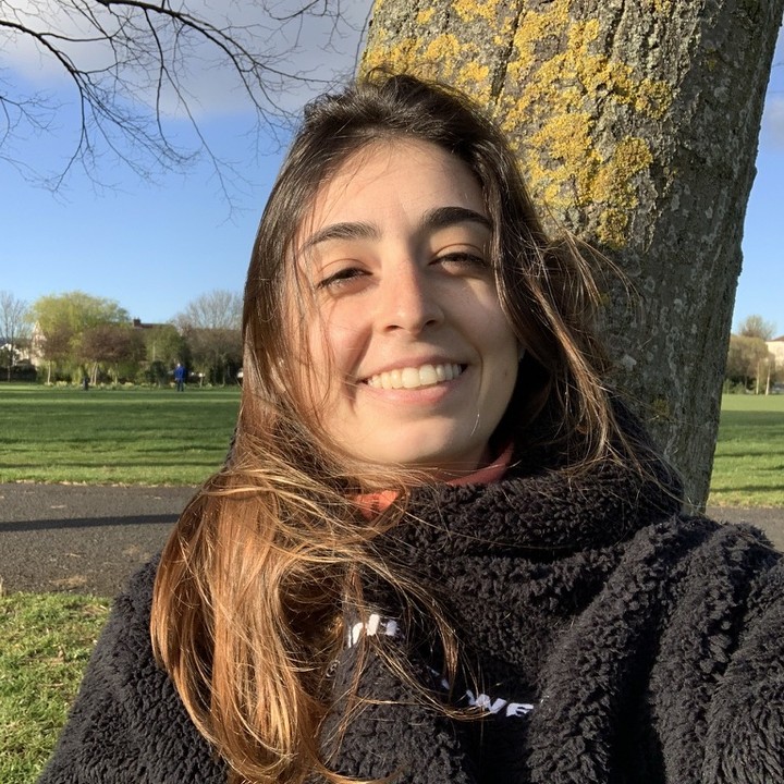mari staüb sorrindo num parque, com uma árvore atrás
